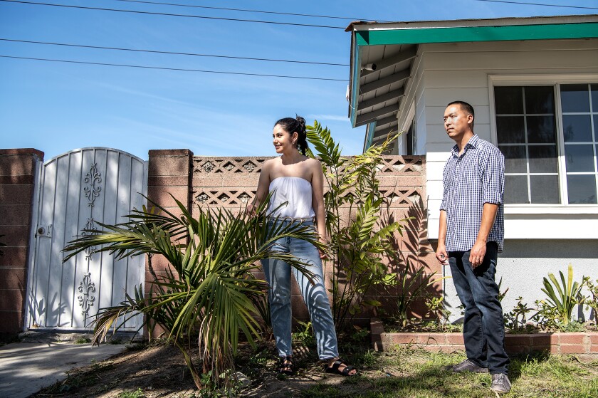 A couple stands outside their home.