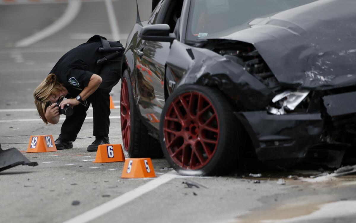 Irvine Police Department CSI Debra Werksman documents the scene of a fatal hit-and-run accident at the intersection of Muirlands Boulevard and Alton Parkway on the morning after Wednesday night's crash.