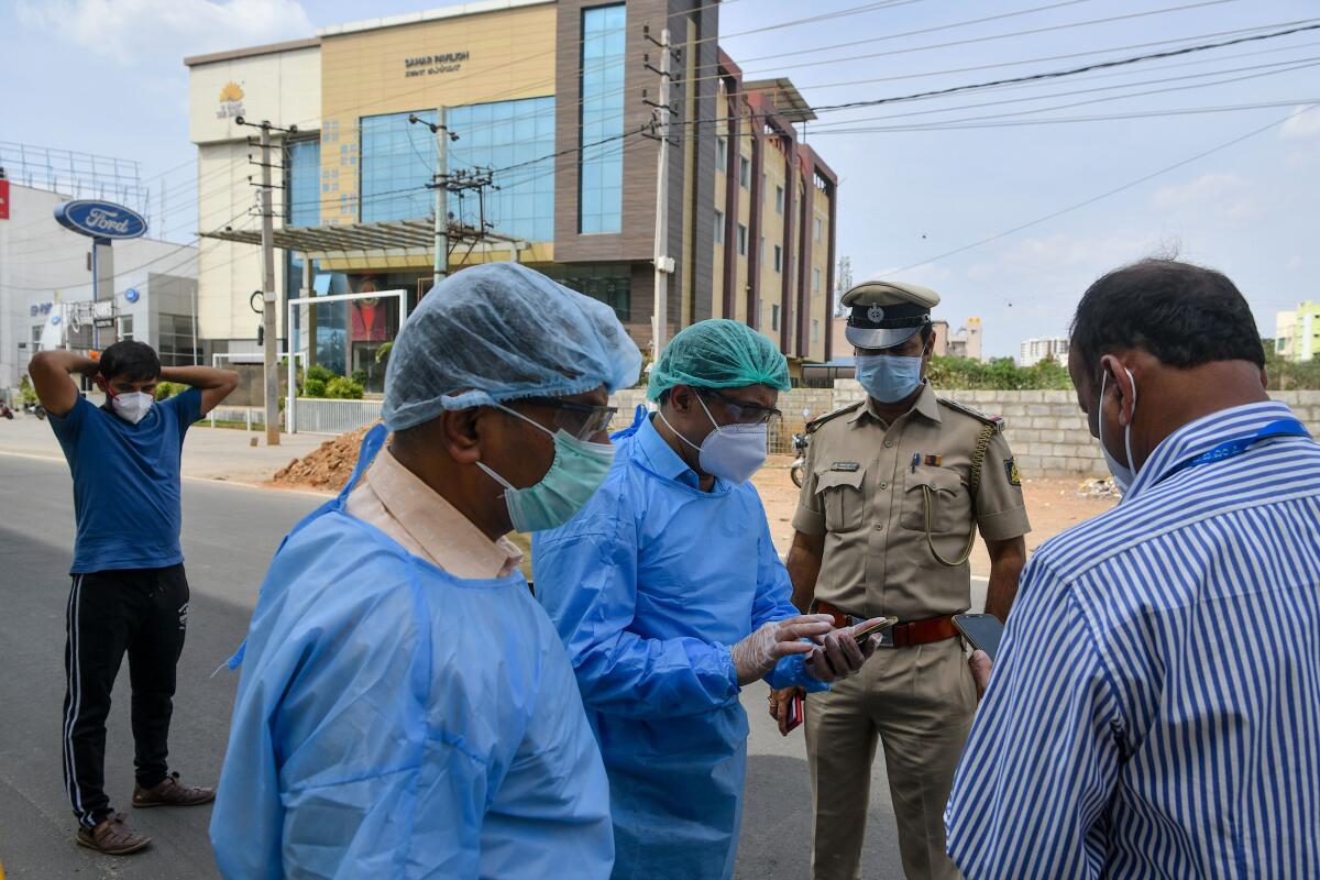 Paramedics and police officials in Bangalore, India, plan the evacuation of a suspected COVID-19 patient on March 25.