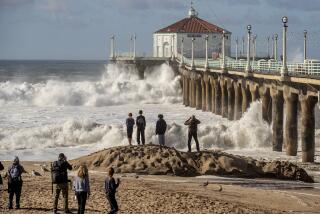 MANHATTAN BEACH, CA-DECEMBER 30, 2023:People watch and photograph as another large wave crashes against the Manhattan Beach Pier. The pier was closed to the public due to the high surf. (Mel Melcon / Los Angeles Times)