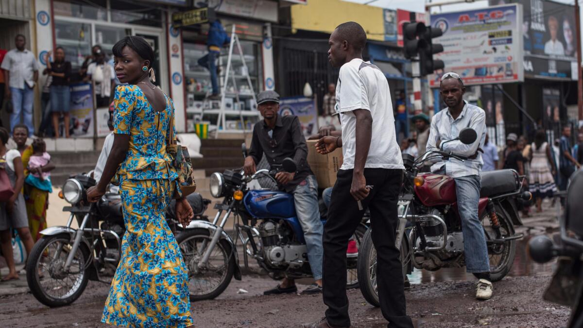 A woman crosses a street in the Matonge district of Kinshasa, the Congolese capital that is home to more than 10 million people, in March 2015.