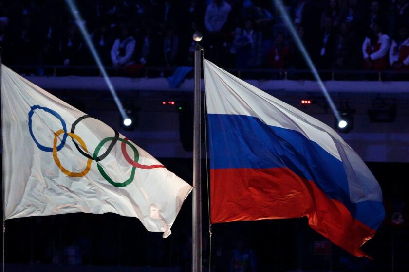 The Russian flag flies next to the Olympic flag during the closing ceremony of the Winter Olympics in Sochi, Russia, on Feb. 23, 2014.