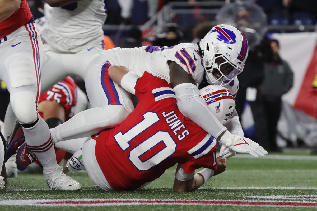 El quarterback Mac Jones (10), de los Patriots de Nueva Inglaterra, es derribado por el defensivo Shaq Lawson, de los Bills de Buffalo, en la primera mitad del partido de la NFL en Foxborough, Massachusetts, el jueves 1 de diciembre de 2022. . (AP Foto/Michael Dwyer)