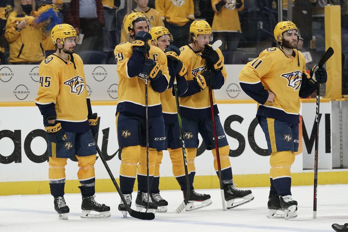 Nashville Predators players watch as Colorado Avalanche players celebrate after Game 4 of an NHL hockey first-round playoff series Monday, May 9, 2022, in Nashville, Tenn. The Avalanche won 5-3 to sweep the series 4-0. (AP Photo/Mark Humphrey)