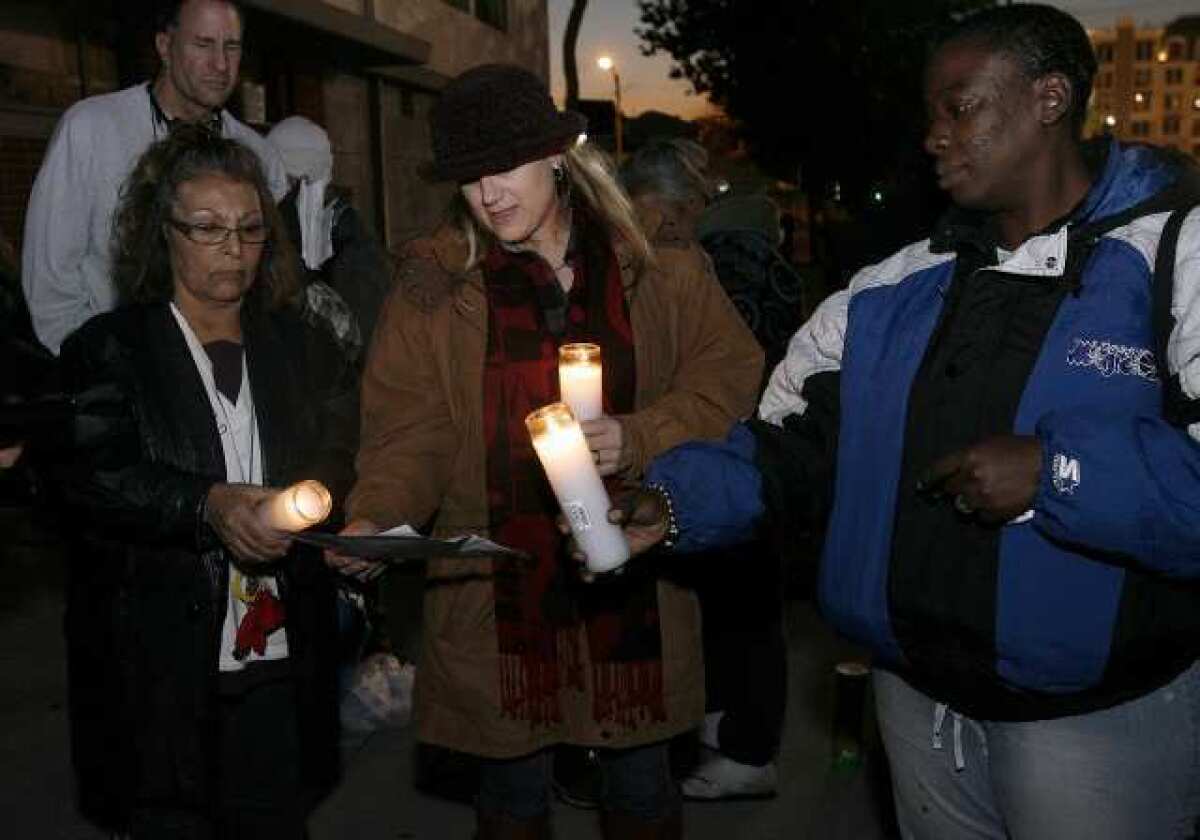 Ascencia Executive Director Natalie Komuro, center, read off names during a brief memorial to remember homeless and former homeless who died during the year, in front of the Glendale National Guard. At left is Ascencia Volunteer & Special Programs manager Elizabeth Tismeer and at right is Shauntail Smith.