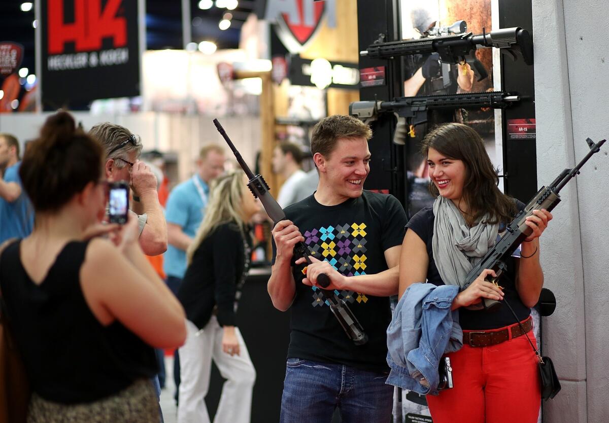 Two attendees pose with assault rifles at an NRA convention.