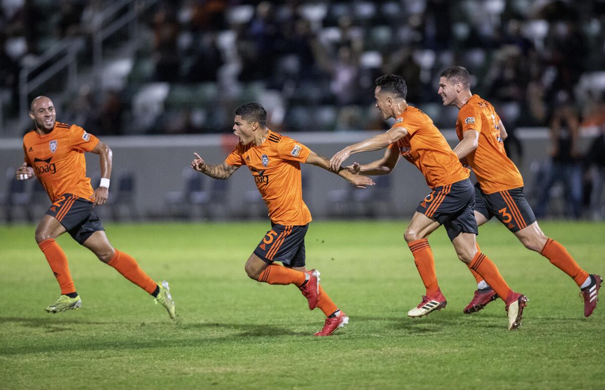 Orange County Soccer Club's Eric Calvillo, center, celebrates after scoring a goal on a free kick.