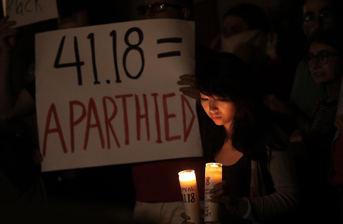 Jane Nguyen with candles and a sign at a rally