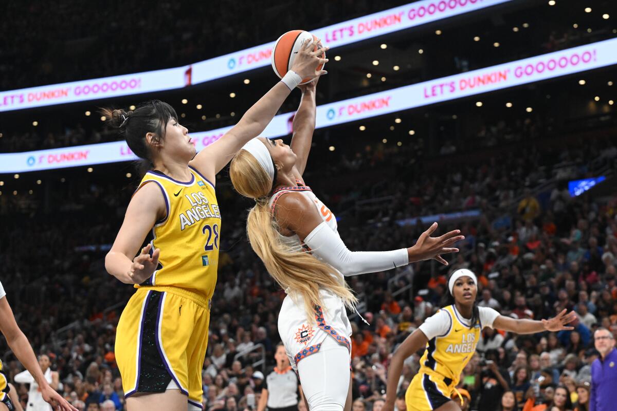 Sparks center Li Yueru, left, reaches with her left arm above Sun forward DiJonai Carrington to block her left-handed layup.