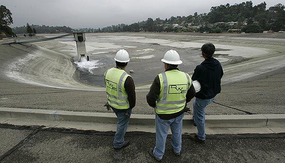 Los Angeles Department of Water and Power employees watch the refilling of Silver Lake Reservoir on Wednesday after it was drained earlier this year because of carcinogens in the lake.