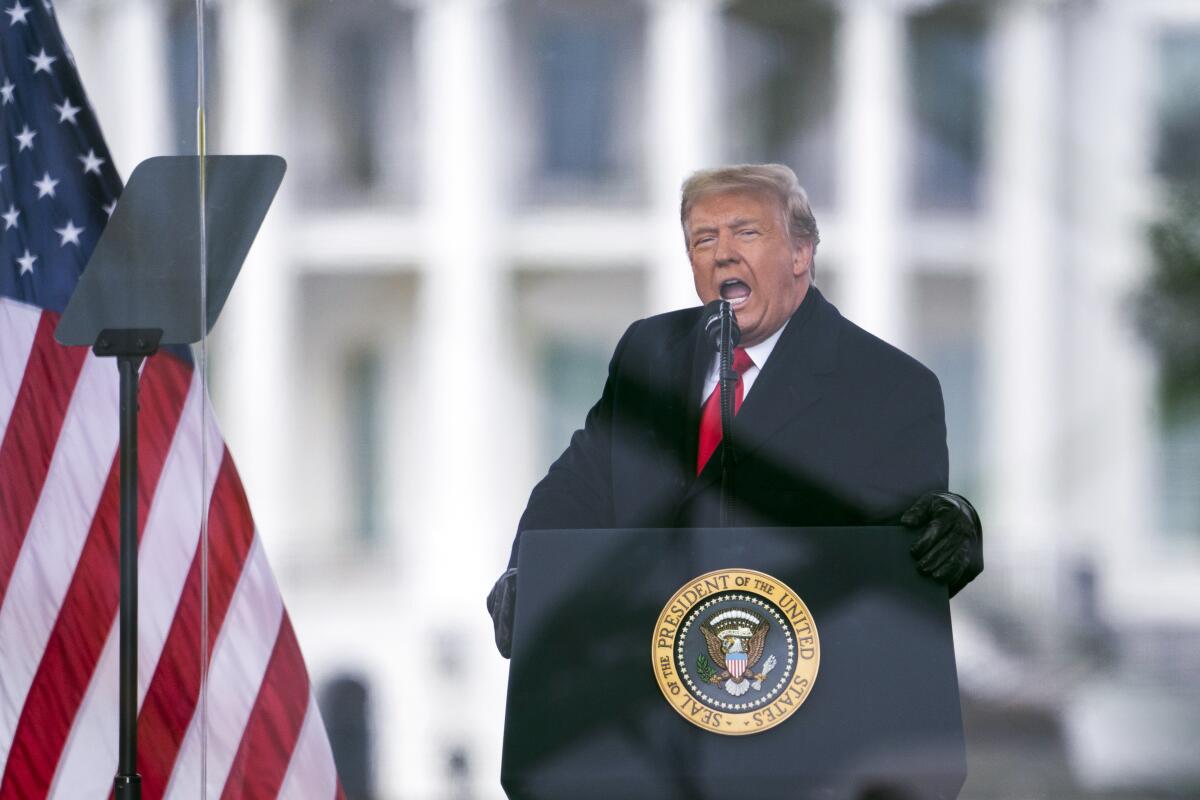 A man in dark suit and red tie speaks at a lectern with a U.S. presidential seal, next to a U.S. flag