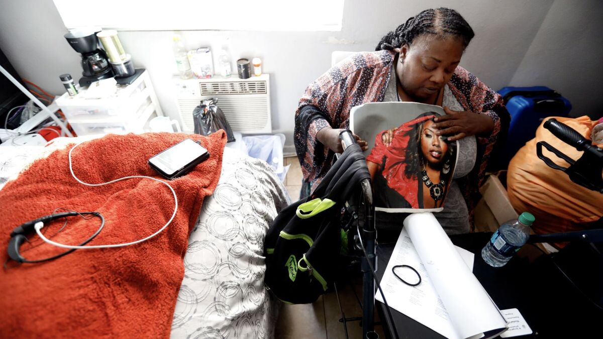 Natalie Purnell looks at a picture of her daughter inside her room at a former motel being used to house homeless women and children. She landed a shared room in the Figueroa Street building a year ago.