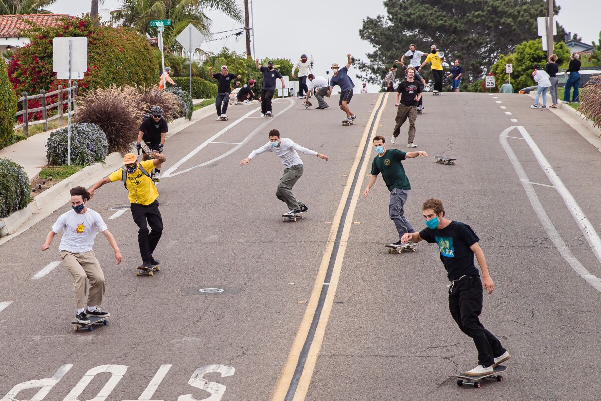 Skateboarders head down a hill on Santa Fe Drive in Encinitas for Sunday's Pushing for Peace protest.