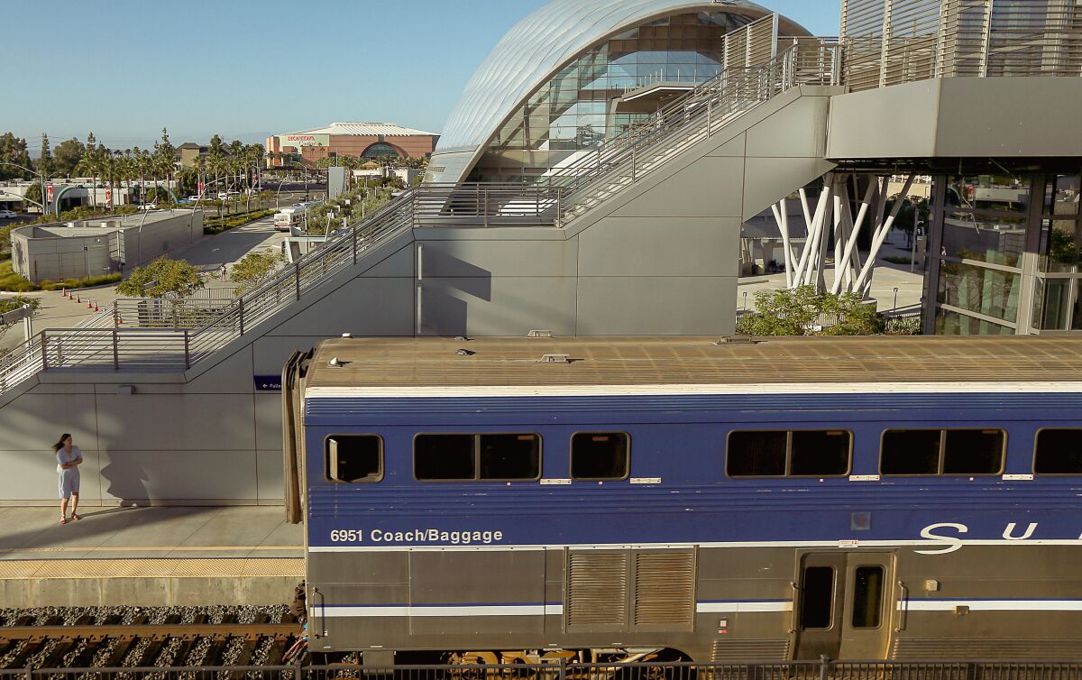 A blue passenger train pulls into a futuristic-looking train station