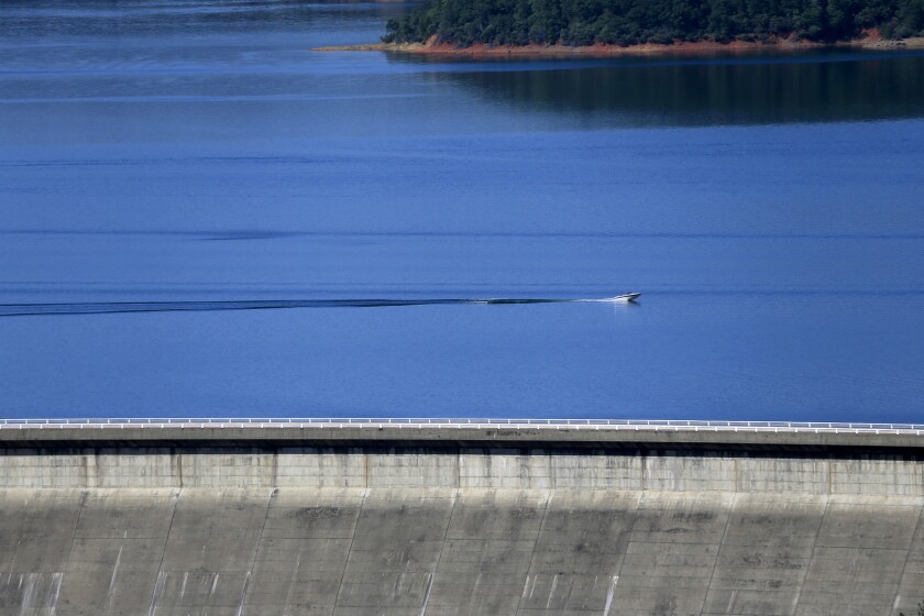 A boater speeds formerly drought-stricken Shasta Lake near its dam.