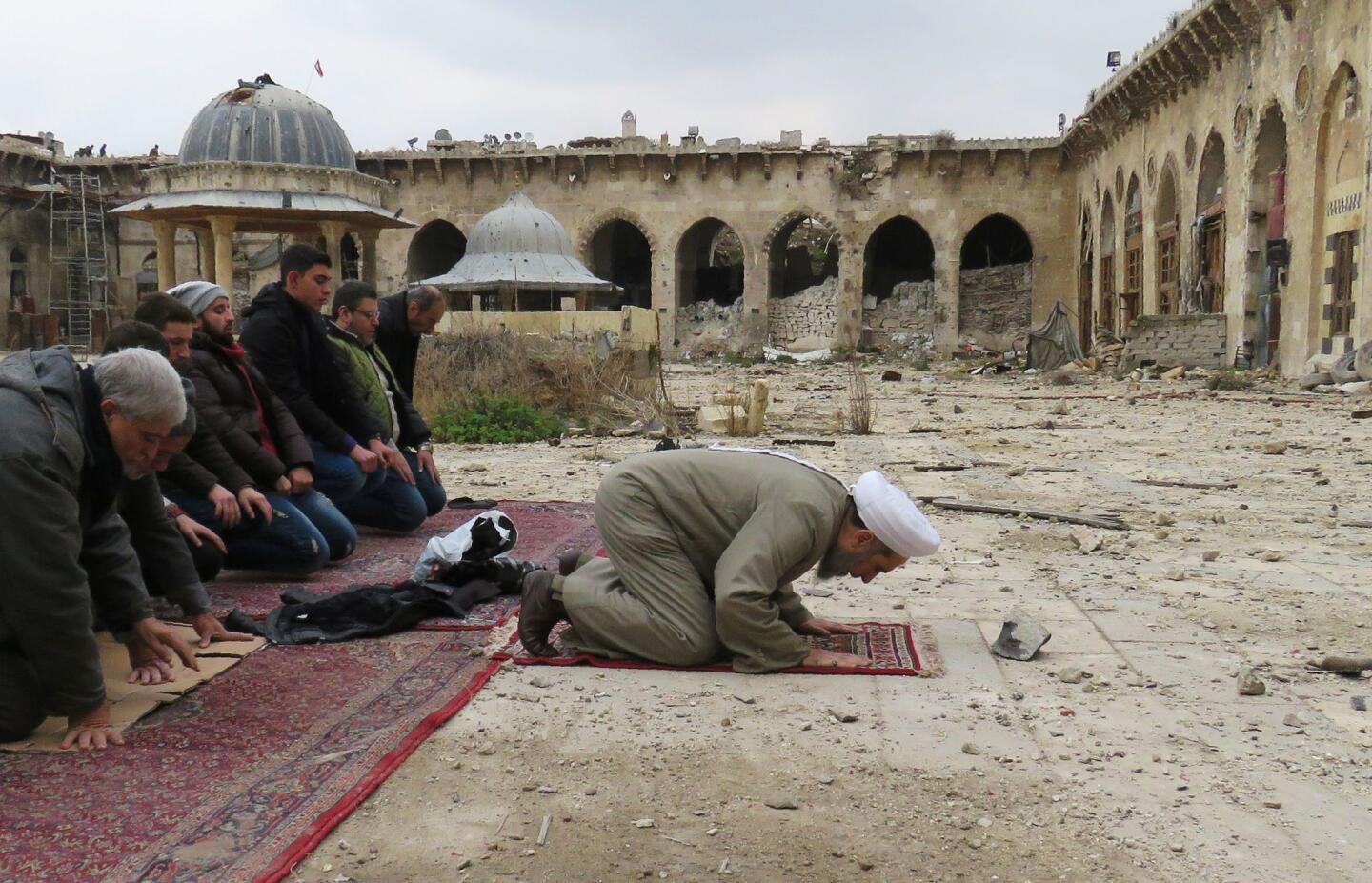 Syrians pray in the ancient Umayyad mosque in the old city of Aleppo, as civilians are allowed access to some neighbourhoods recently retaken by Syrian government forces.