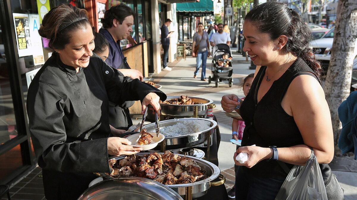 Lola's Peruvian Restaurant's employee Sandra Loli serves Eva Flores, who works in Glendale, at the Taste of Downtown Glendale in 2017.