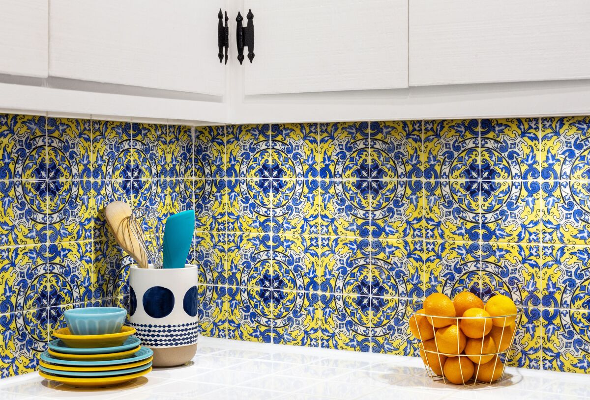This image provided by The Spruce shows peel-and-stick in a kitchen. The experts at The Spruce recommend peel-and-stick as a budget-friendly, instant upgrade for spaces like the kitchen backsplash. This colorful variety even looks like tile. (Aubrey Hays and Niv Rozenberg/The Spruce via AP)