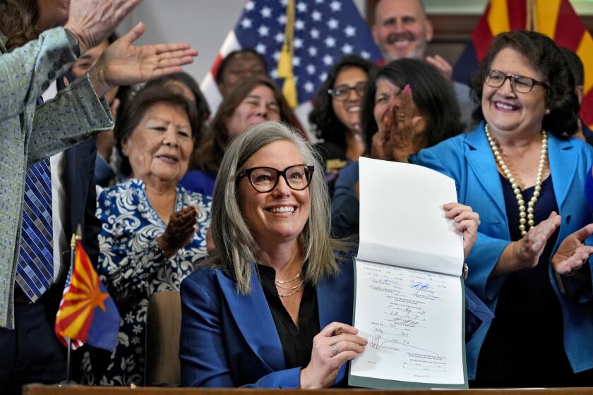 FILE - Arizona Gov. Katie Hobbs holds up the repeal of the Civil War-era near-total abortion ban, May 2, 2024, at the Capitol in Phoenix. Arizona's highest court on Monday, May 13, gave the state's attorney general another 90 days to decide further legal action in the case over a 160-year-old near-total ban on abortion that lawmakers recently voted to repeal. (AP Photo/Matt York, File)