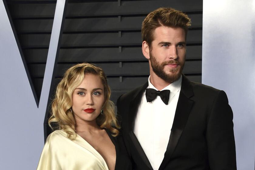 FILE - In this March 4, 2018 file photo, Miley Cyrus, left, and Liam Hemsworth arrive at the Vanity Fair Oscar Party in Beverly Hills, Calif. Though Cyrus and Hemsworth lost their home in the deadly wildfire blazing California, they are donating $500,000 to The Malibu Foundation through Cyrus charity, The Happy Hippie Foundation. (Photo by Evan Agostini/Invision/AP, FIle)