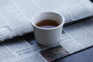 A cup of tea rests on top of a Vietnamese newspaper at Coffee Factory.