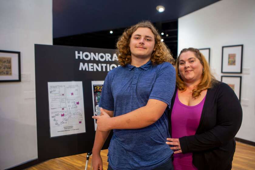 Gabriel Trepashko (pointing to his entry) with his mother, Tanya Trepashko, at the awards ceremony in the Comic-Con Museum.