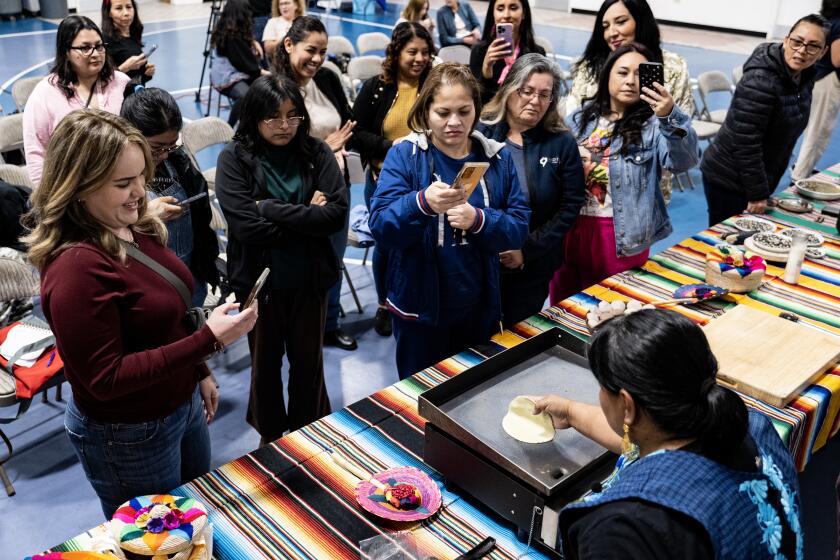 San Diego, CA - March 14: SunCoast Market Co-op kicks off its weekly Healthy Cooking Workshops Thursday, March 14, 2024, with special guest chef Ron Oliver at Boys and Girls Club of South County. Soiree Vasquez explains how to turn masa into tortillas and answers questions about the cooking process as attendees gather around her. (Luke Johnson / For The San Diego Union-Tribune)