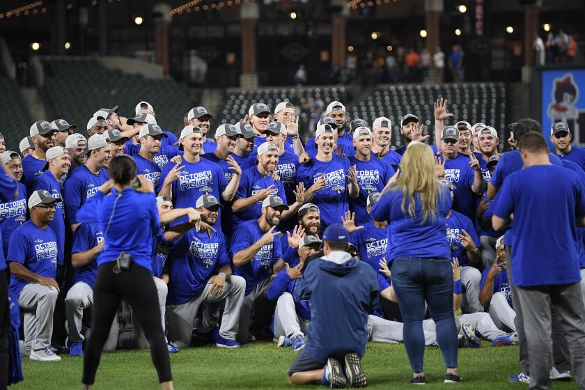 Members of the Los Angeles Dodgers pose for photos on the field after a baseball game against the Baltimore Orioles, Tuesday, Sept. 10, 2019, in Baltimore. The Dodgers won 7-3, clinching their seventh consecutive NL West title. (AP Photo/Nick Wass)
