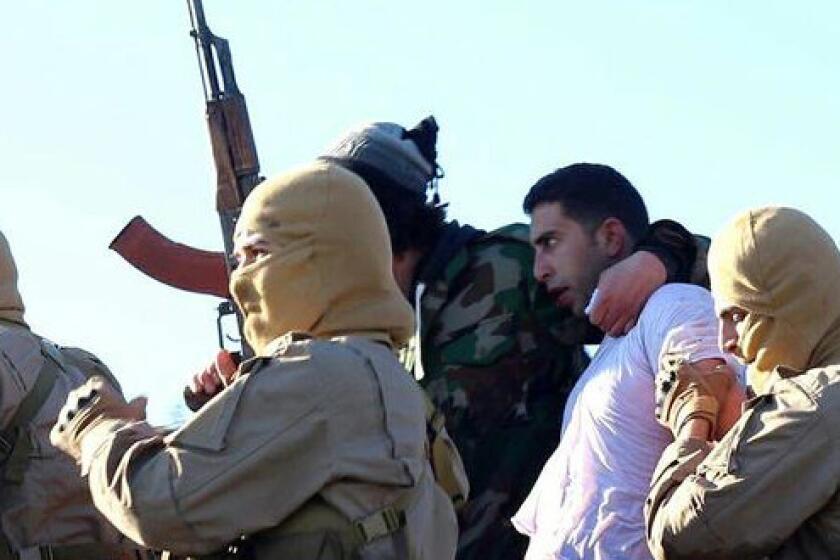 This image posted by the Raqqah Media Center, which monitors events in territory controlled by Islamic State militants with the permission of the extremist group, reportedly shows militants with the captured Jordanian pilot in Raqqah, Syria, on Dec. 24.