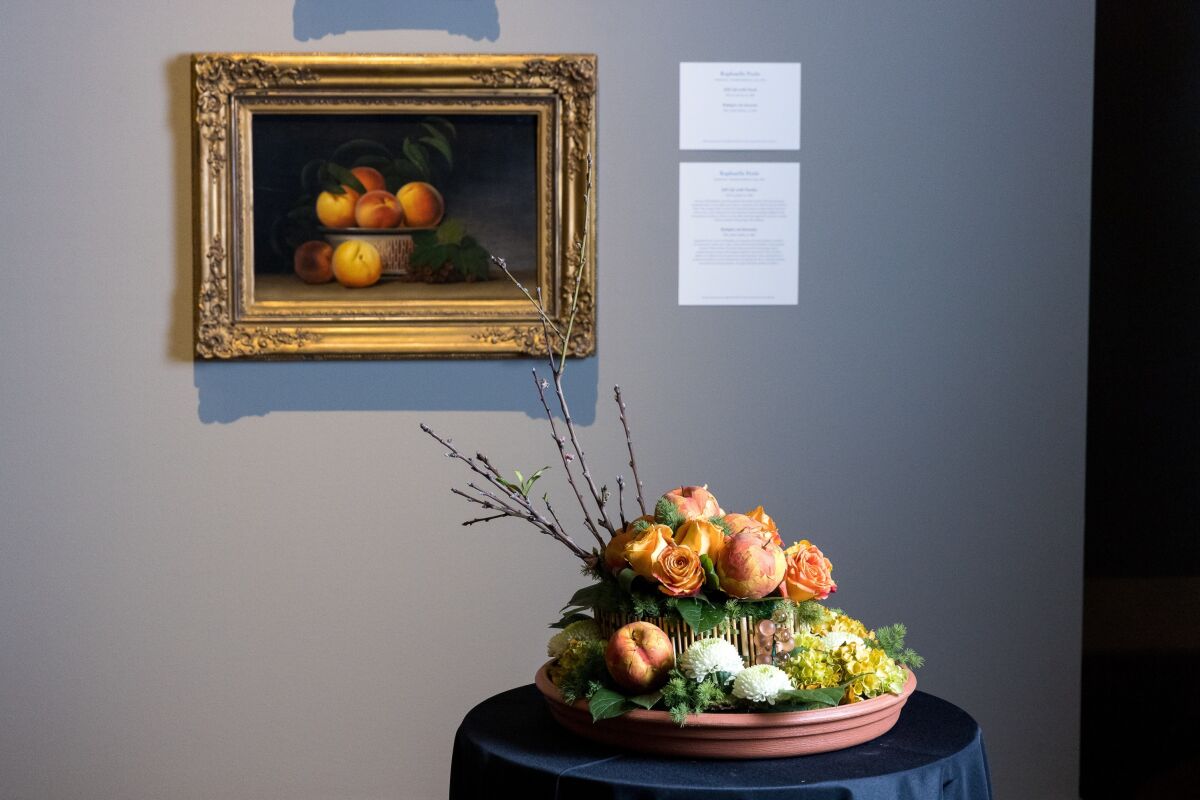 A flower display next to a painting at the San Diego Museum of Art.