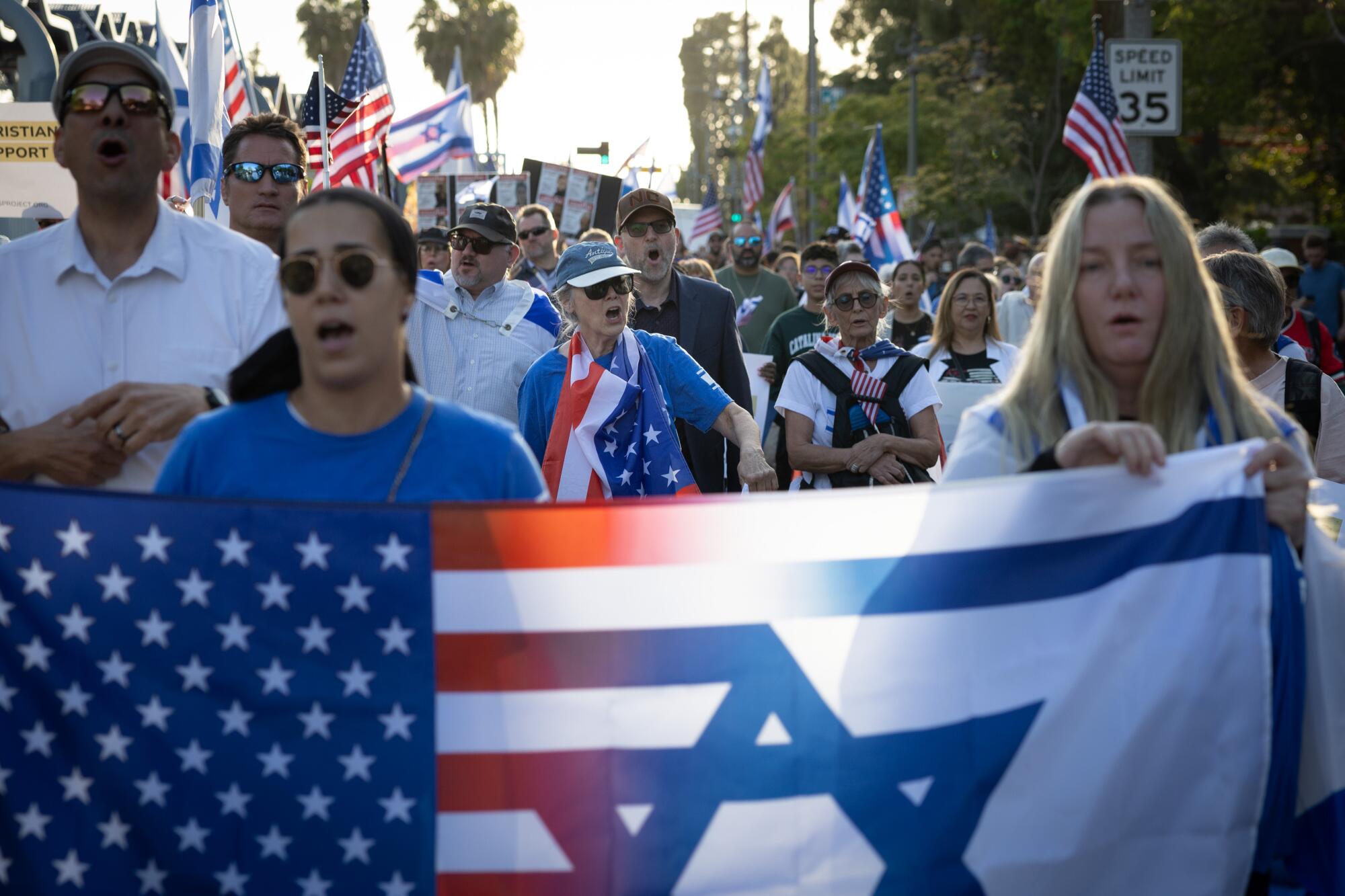 A protestor in support of Israel waves an Israeli flag while surrounded by pro-Palestinian