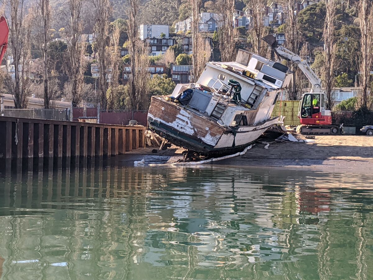 Officials prepare to crush an old boat at the dock of U.S. Army Corps of Engineers in Sausalito.
