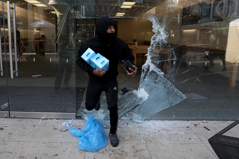 Looters steal from the Apple Store at The Grove shopping mall on Saturday while protesters march the