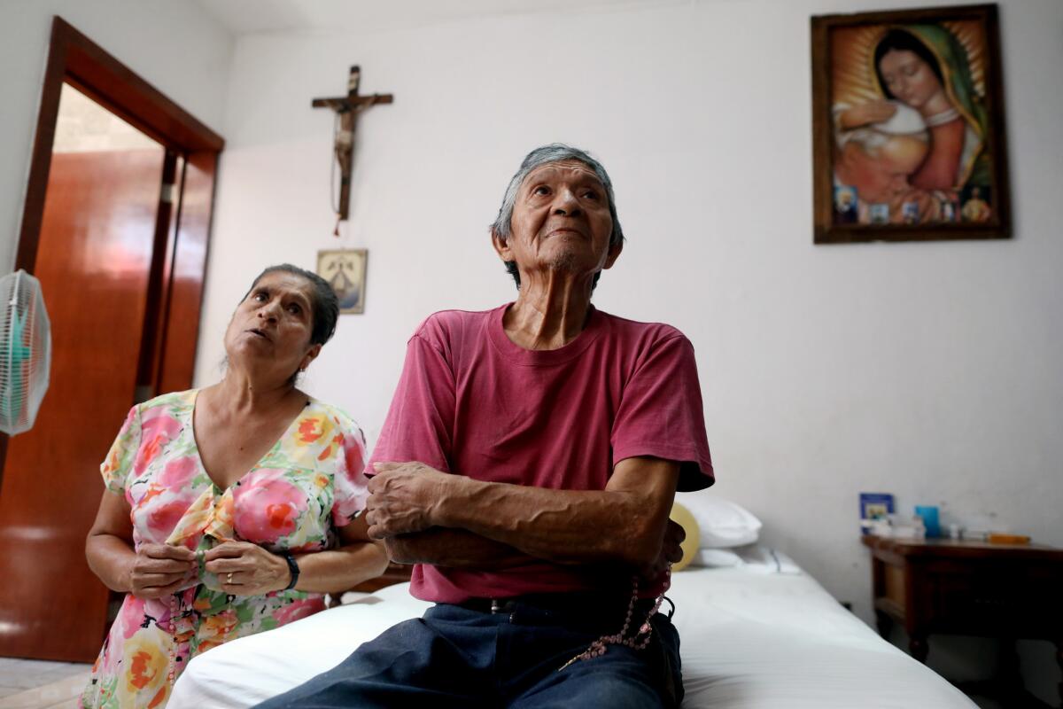 Maria Guadalupe Hernandez, left, and husband Juan Hernandez Hernandez, pray the rosary while Catholic images are shown on their television at their home of 35-years in colonia Lagos de Oriente in Guadalajara. (Gary Coronado / Los Angeles Times)