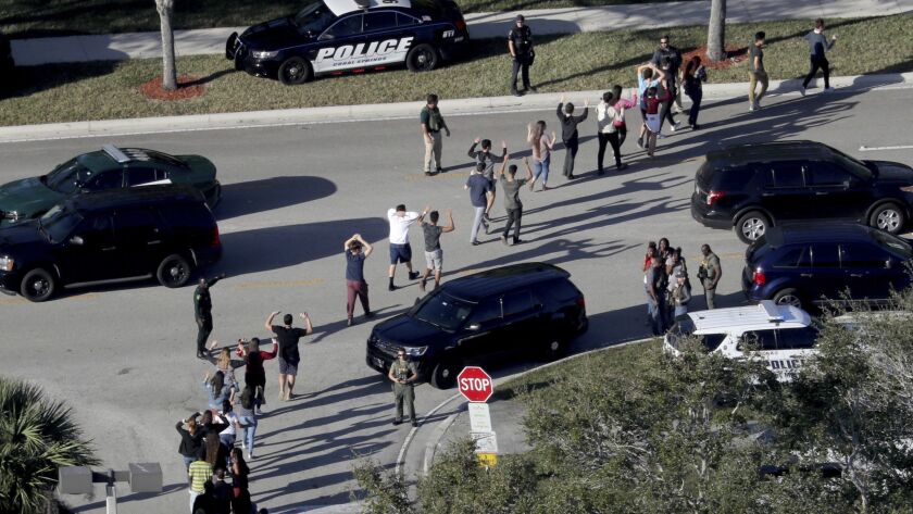 Students hold their hands in the air as they are evacuated by police from Marjory Stoneman Douglas High School in Parkland, Fla., after a shooter opened fire on the campus in February 2018. A law passed in response was challenged in court Monday.