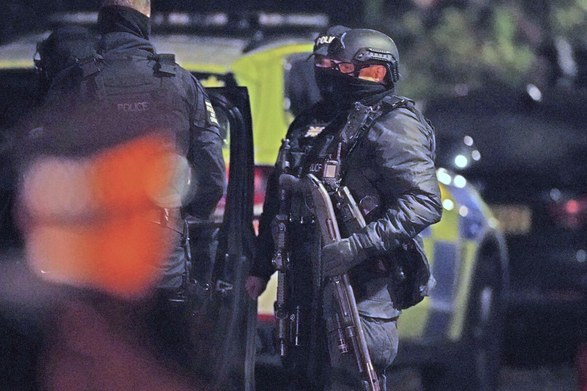 An armed police officer holds a breaching shotgun, used to blast the hinges off a door, at an address in Rutland Avenue in Sefton Park, after an explosion at the Liverpool Women's Hospital in Liverpool, England, Monday, Nov. 15, 2021. British police arrested three men under terrorism laws Sunday after a car exploded outside the hospital, killing one man and injuring another. (Peter Byrne/PA via AP)