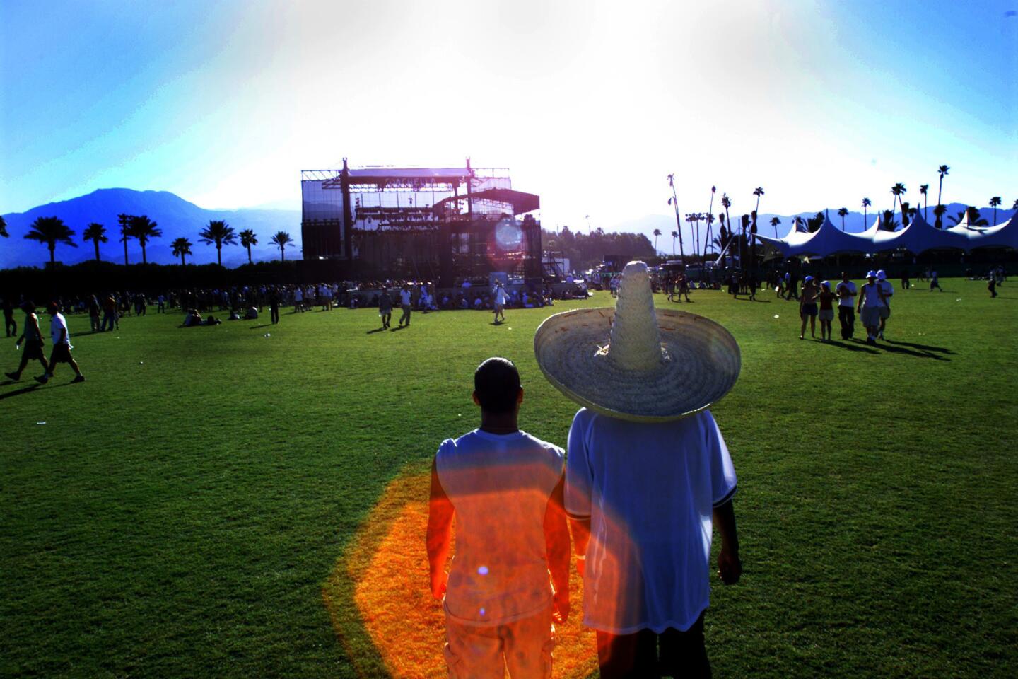 Dennis Carrillo wears a sombrero as a shield against the blistering sun as he and friend Dario Soto, both of Los Angeles, walk toward the stage at the Coachella Music Festival Oct. 9, 1999.
