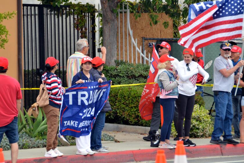 A man carrying a red Trump flag shouted at a man videotaping him on Bayside Drive during a Trump rally.