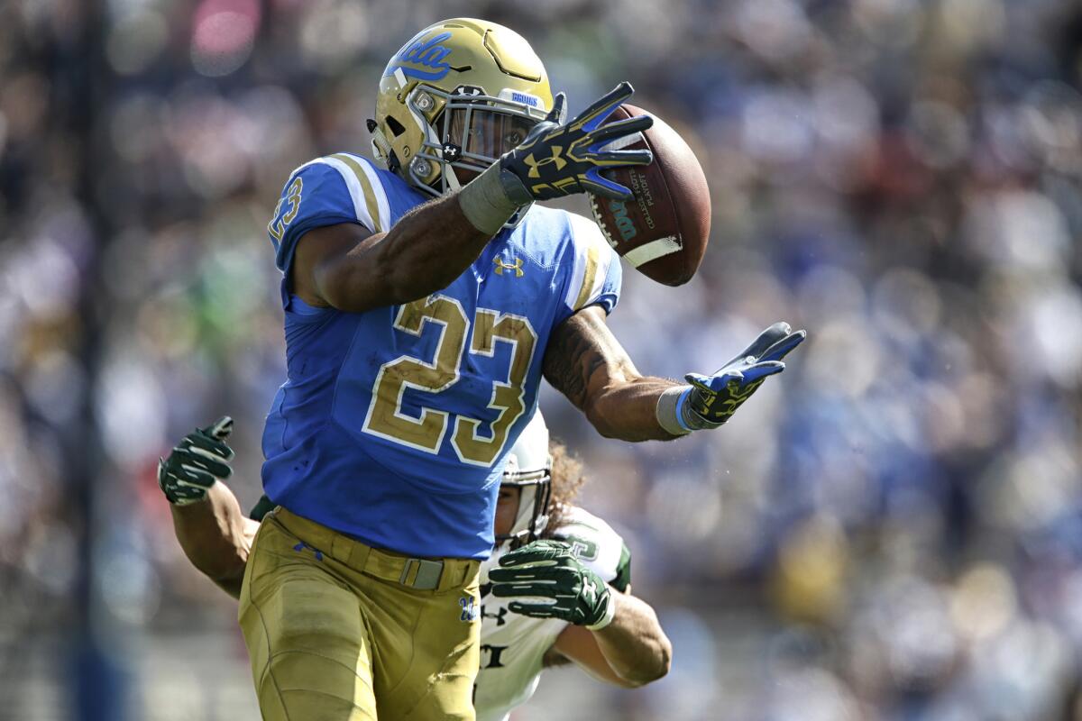 UCLA running back Nate Starks hauls in a long pass from quarterback Josh Rosen as Hawaii linebacker Jahlani Tavai chases during the second quarter.