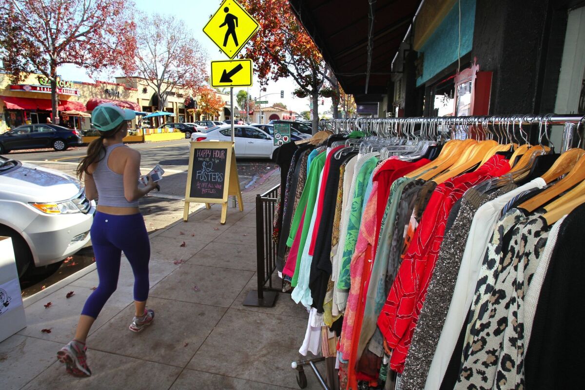November 30, 2013, Carlsbad, California, USA_| Small Business Saturday- A morning jogger on State Street in downtown Carlsbad passes by a sidewalk display of clothing for sale in front of the Dana G Boutique. (Charlie Neuman/UT San Diego/Copyright 2013 San Diego Union-Tribune, LLC)