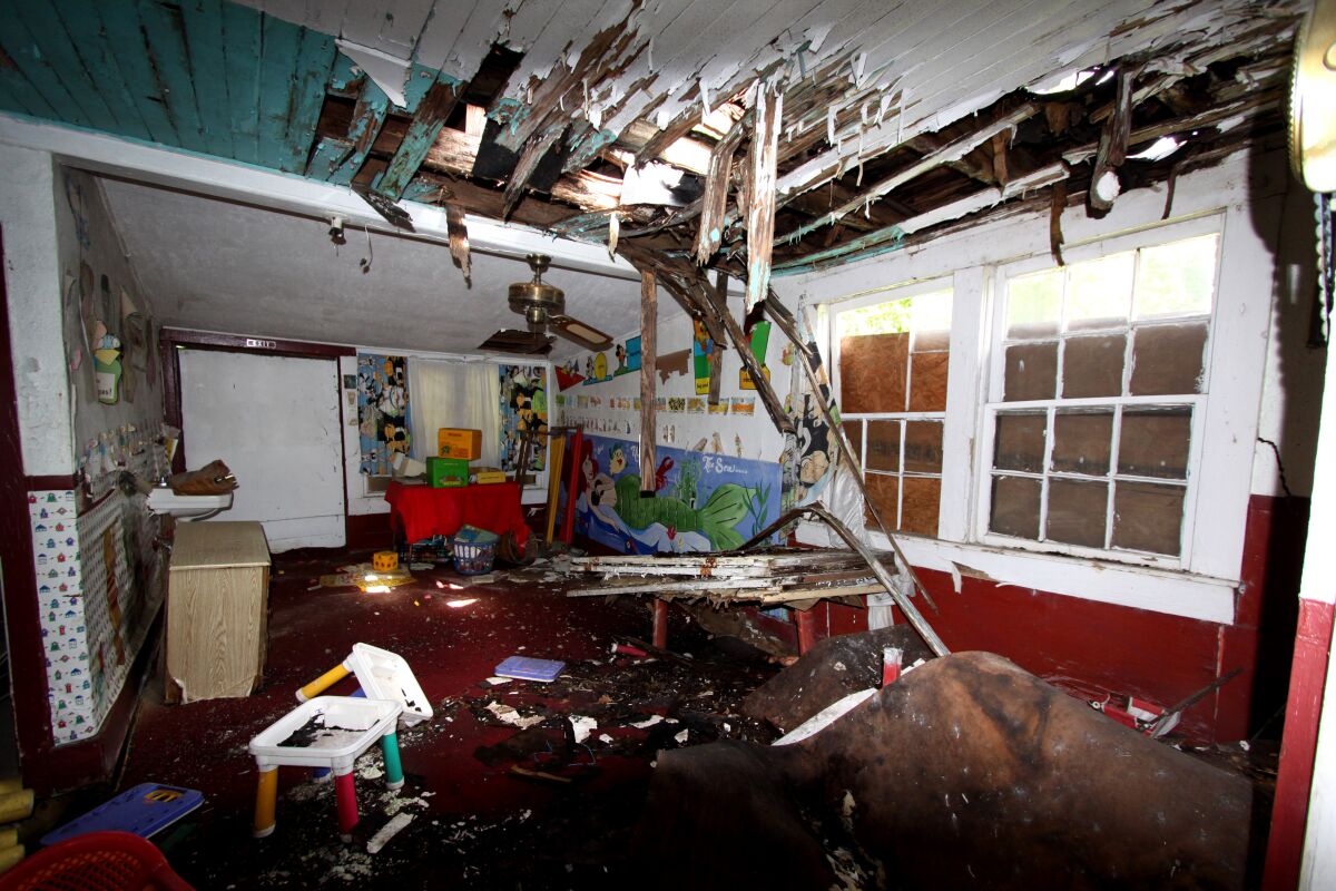 The interior space of a home is nearly destroyed as a roof caves in leaving debris covering the space.