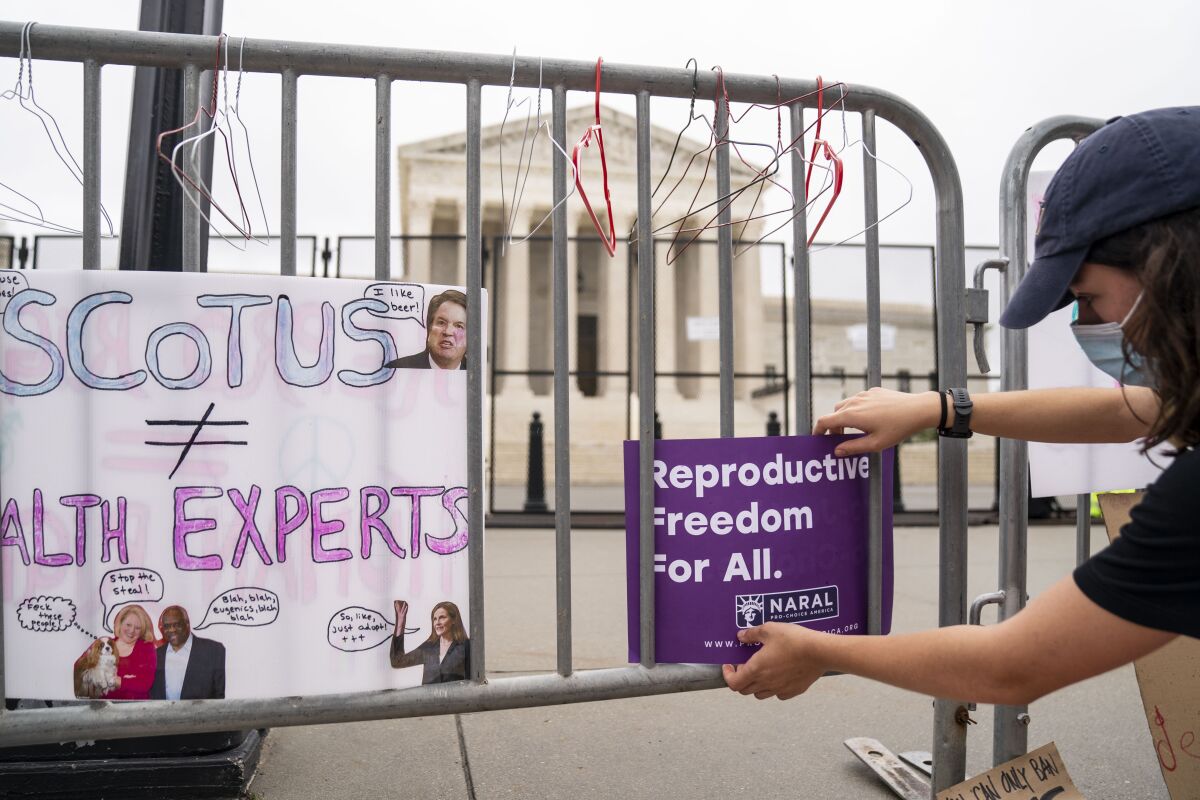 An abortion rights activist puts a sign on a barrier surrounding the Supreme Court