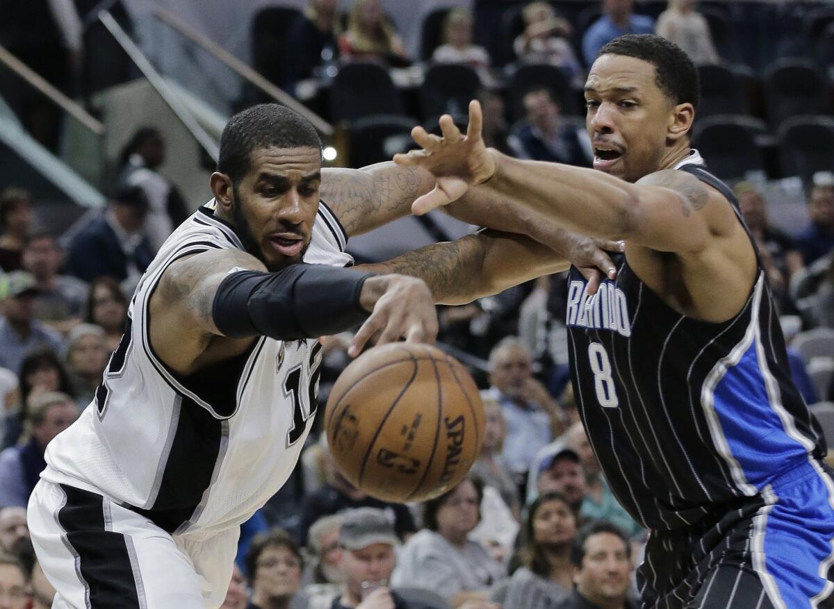Spurs forward LaMarcus Aldridge (12) and Magic forward Channing Frye (8) reach for a loose ball during the second half.