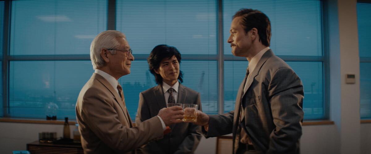 Three men click drink glasses.