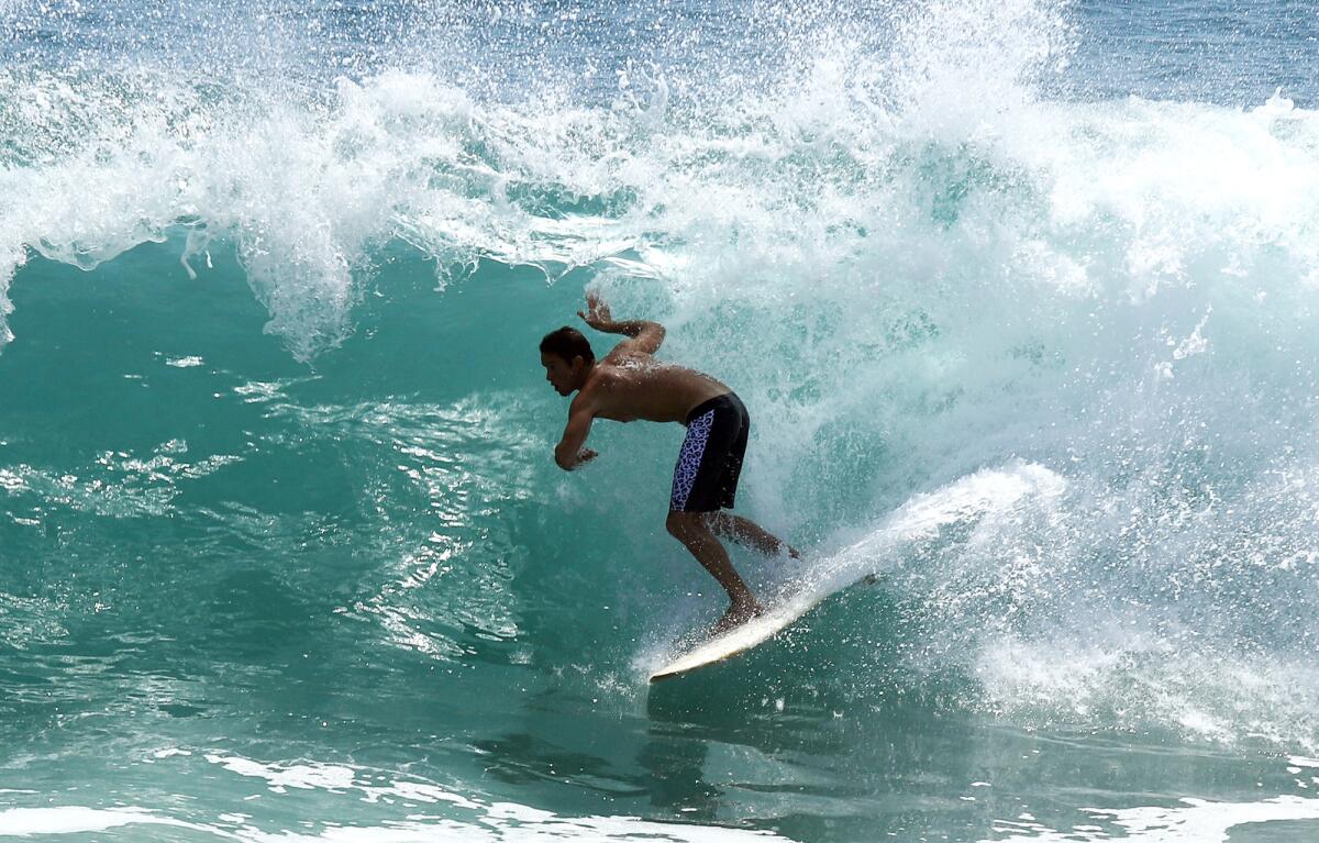 A surfer gets "tubed" on a wave that's well overhead.