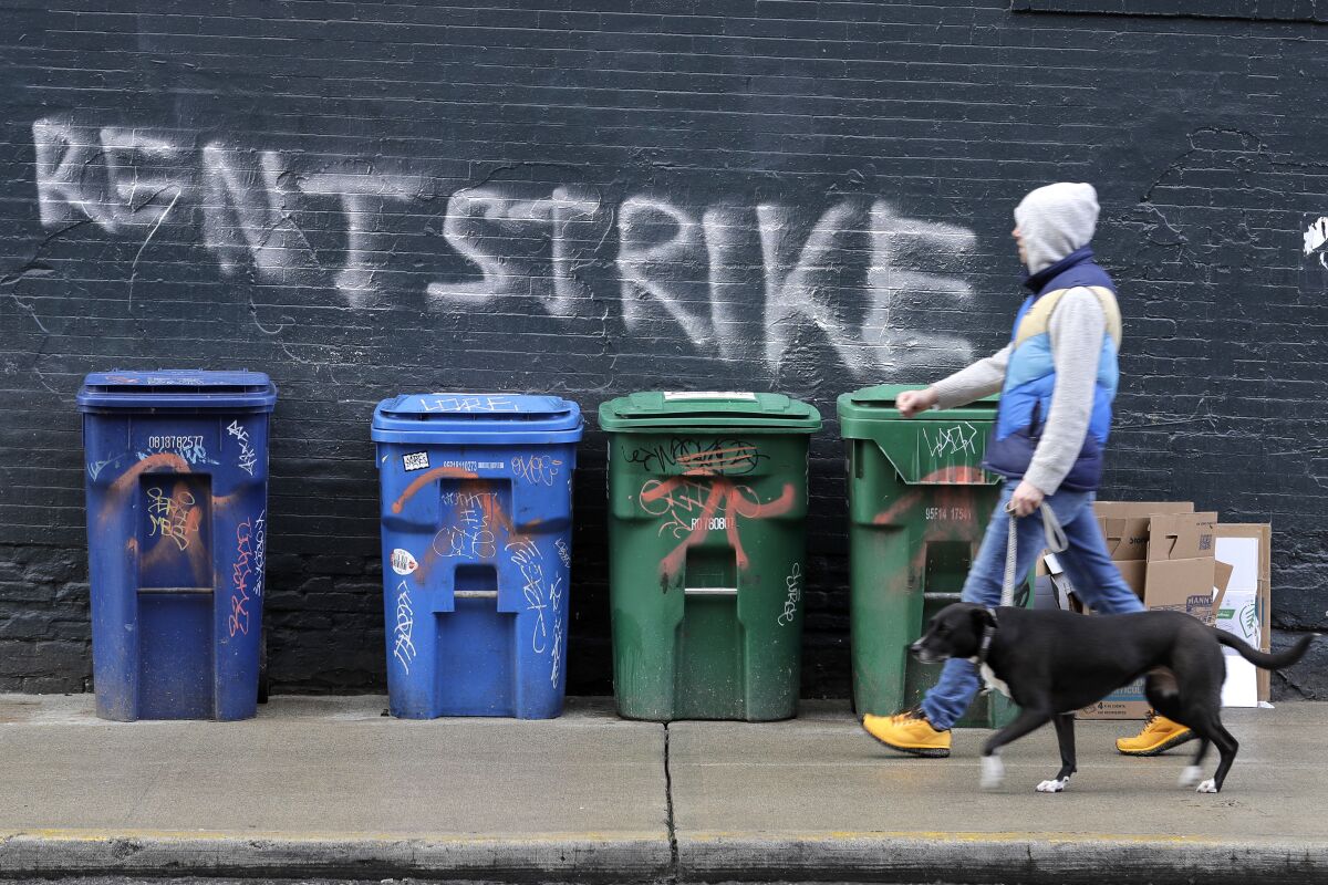 FILE - In this April 1, 2020, file photo, a pedestrian walks past graffiti that reads "Rent Strike" in Seattle's Capitol Hill neighborhood. The White House announced Tuesday, Sept. 1, that the Centers for Disease Control and Prevention would act under its broad powers to prevent the spread of the coronavirus. The measure would forbid landlords from evicting anyone for failure to pay rent, providing the renter meets criteria. (AP Photo/Ted S. Warren, File)