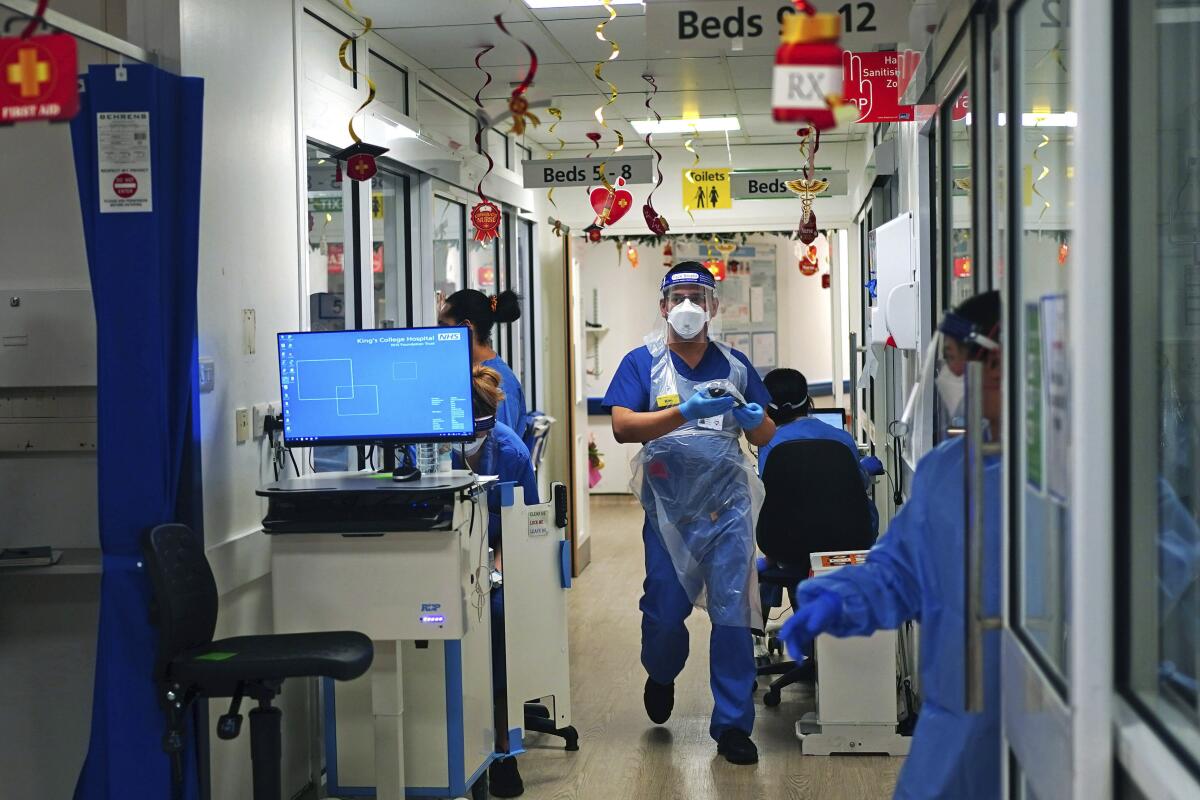 Trabajadores médicos, algunos sentados, otros de pie, en pasillo de hospital
