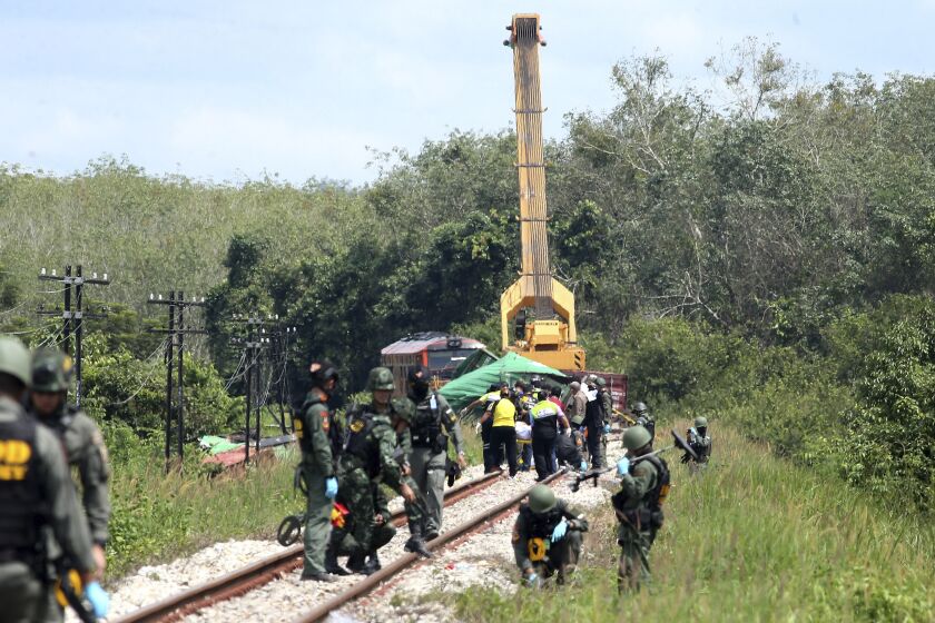 Thai Explosive Ordnance Disposal (EOD) officials examine a section of train track damaged by a bomb blast in Songkhla province, southern Thailand, Tuesday, Dec. 6, 2022. Police said a bomb exploded on the train tracks Tuesday killing and injuring a number of people from the railroad authority who were working along a section of track damaged from an earlier explosion on Dec. 3. (AP Photo)