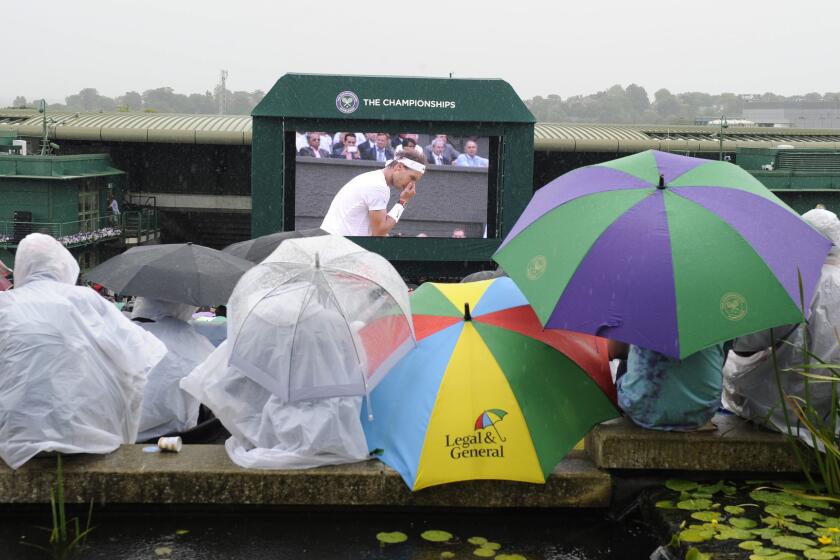 Fans brave the elements as rain interrupts play at Wimbledon on Saturday.