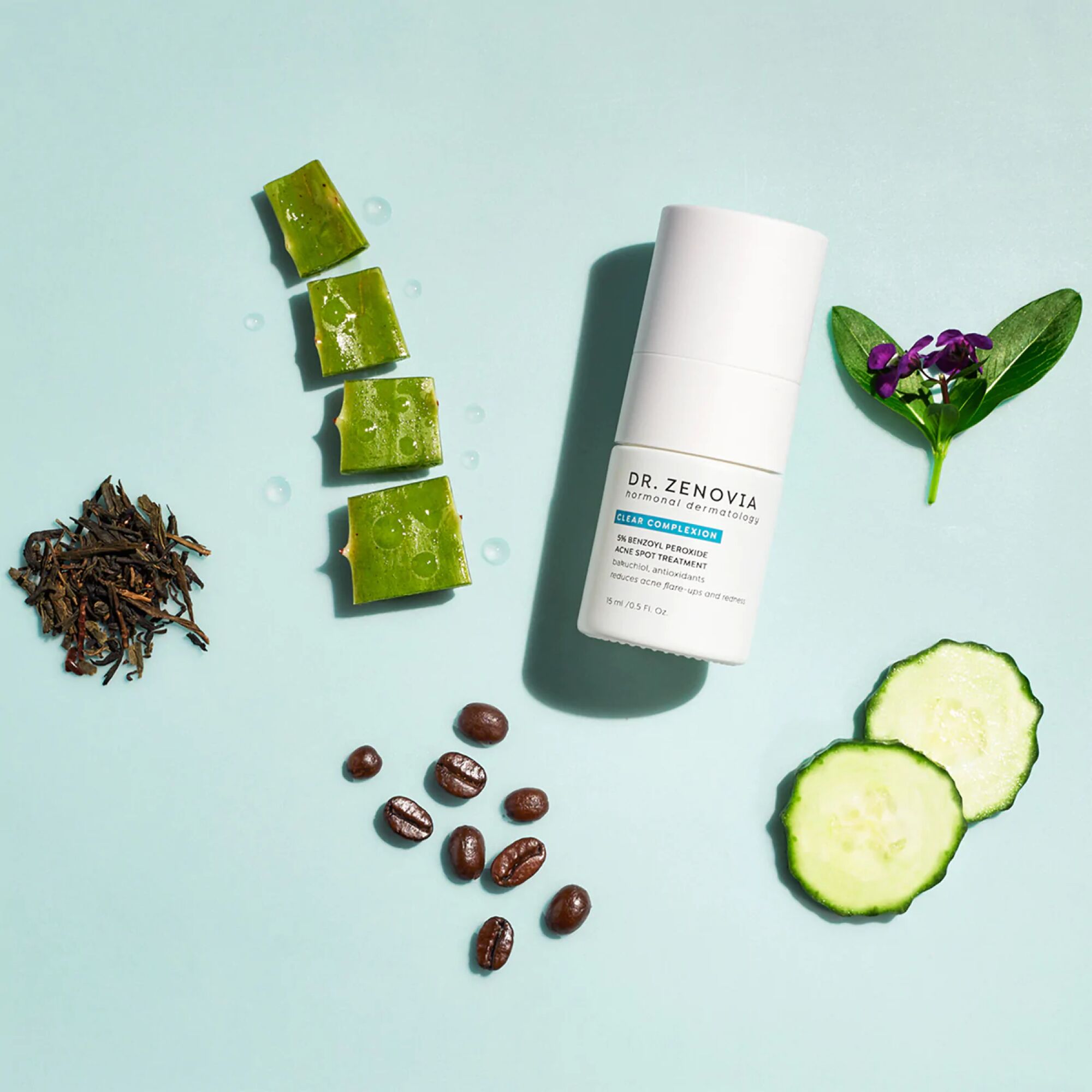 Dr. Zenovia acne spot treatment bottle surrounded by pieces of aloe, cucumber, coffee beans, florals, and dried herbs